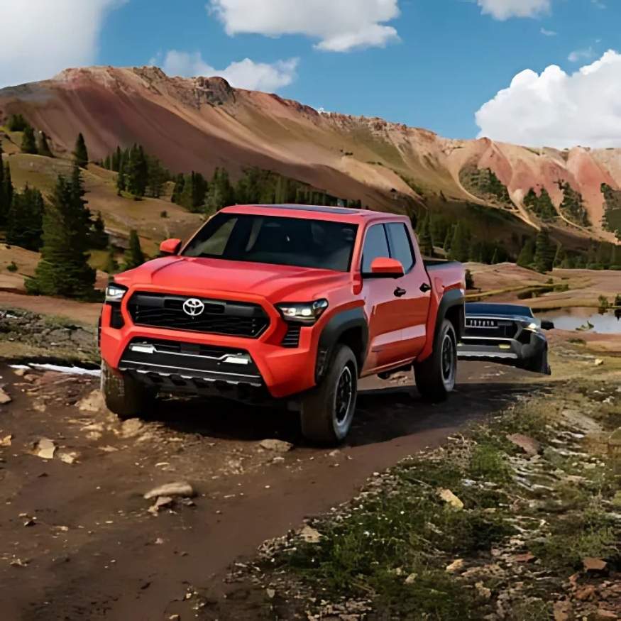 A red Toyota Tacoma drives along a dirt trail through a rugged, mountainous landscape.