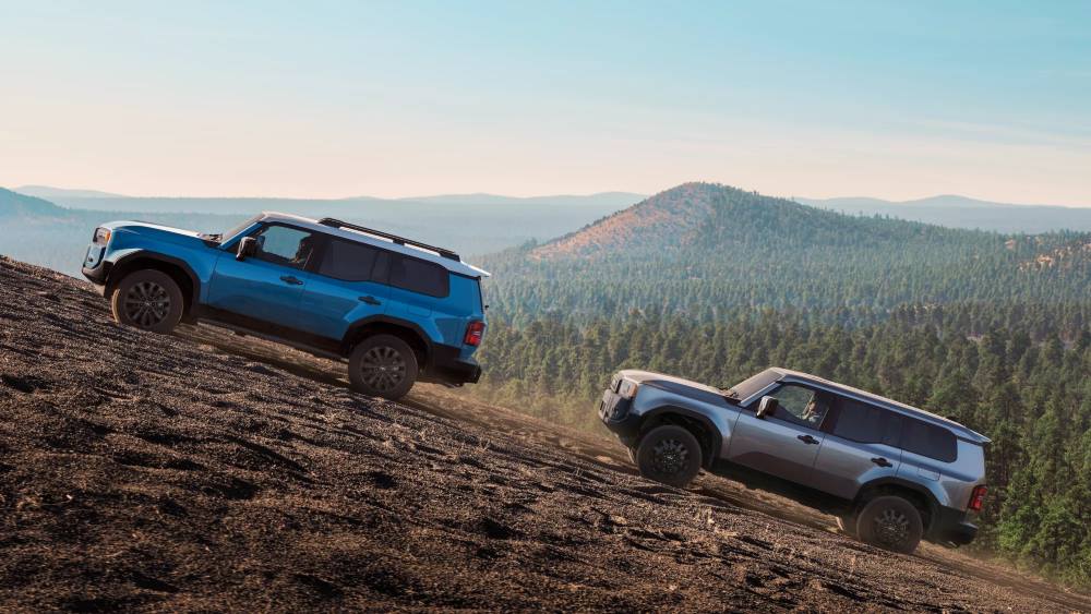 Two Toyota Land Cruisers climbing a steep mountain trail with scenic forest views